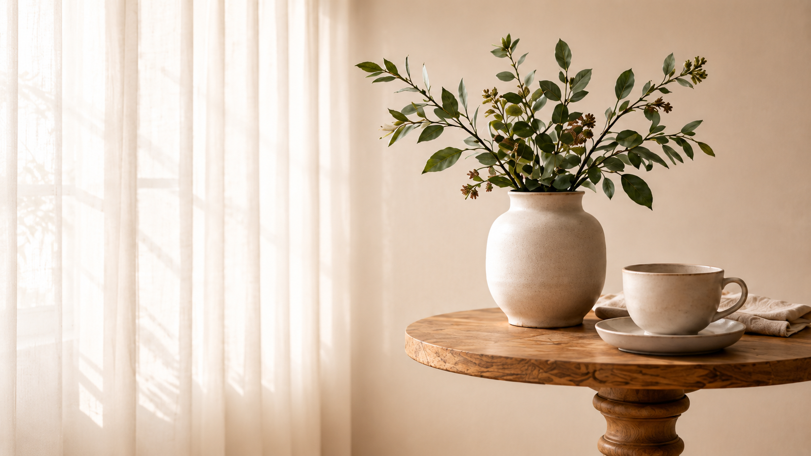 Minimal ceramic vase with greenery and a cup on a wooden table
